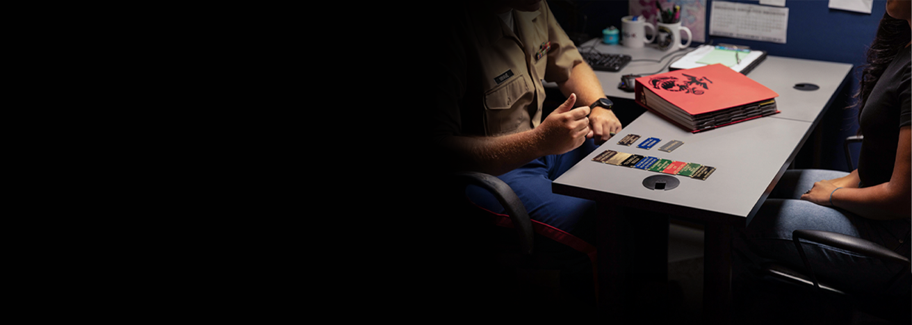 Marine recruiter at desk with recruitment materials and informational brochures in office setting.