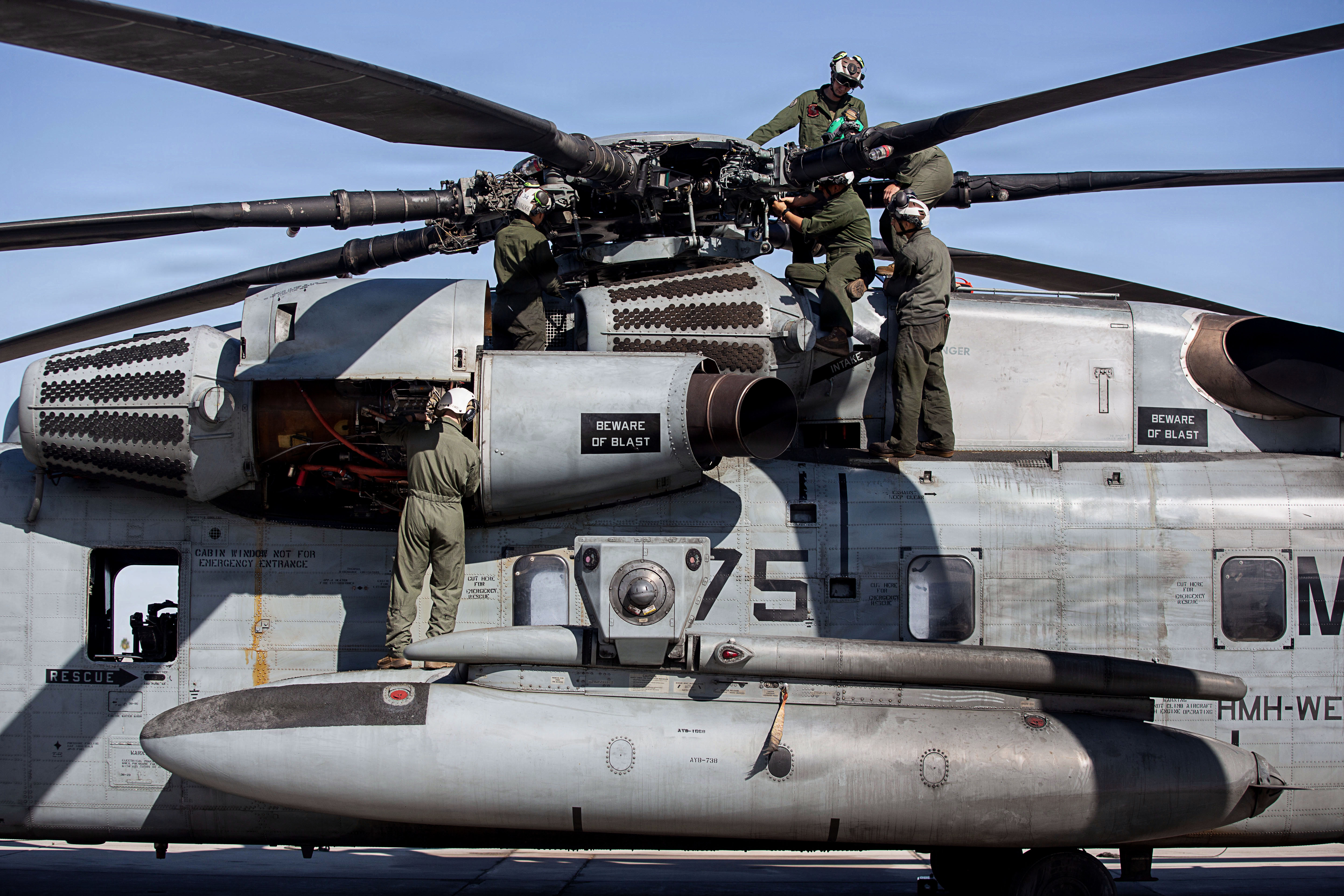 Six aviation mechanic Marines work together to maintain a CH-53K helicopter.