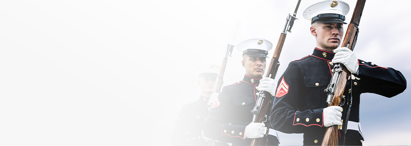 Marines in dress blue uniforms perform ceremonial rifle drill with bayonets fixed at Camp Lejeune.