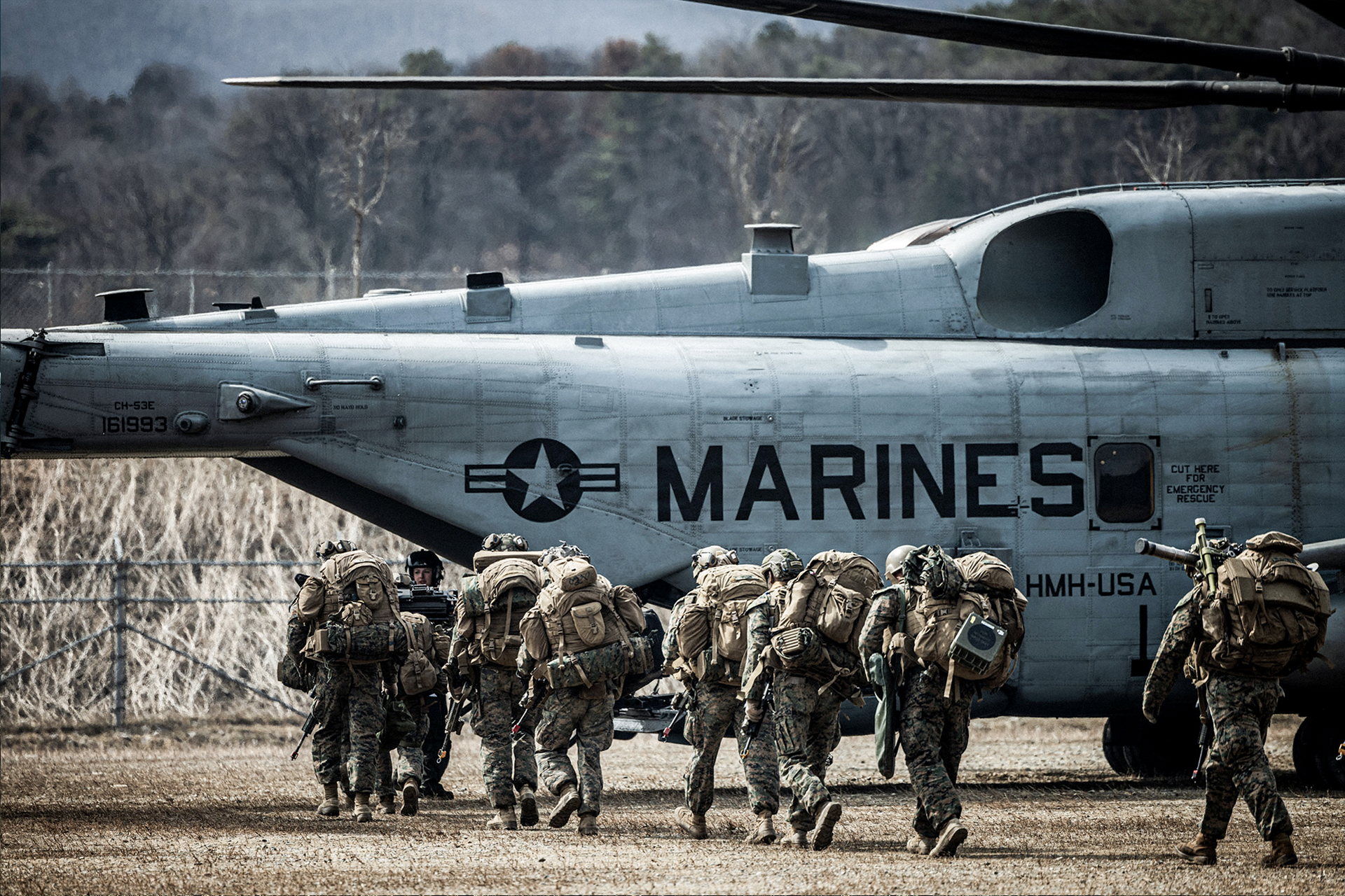 Marines with full gear boarding Marine Corps helicopter during coordinated unit deployment exercise.